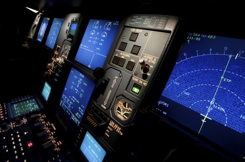 Dark cockpit detail of an Airbus A330 - 200 commercial airliner while crossing the Atlantic at 35000 feet. This is an actual inflight situation photographed from the co-pilot's position, with colorful blue on black screens giving information about engine parameters, navigation, flight parameters and communication. Flood lights on the instrument panels reveal switches and gauges. XL