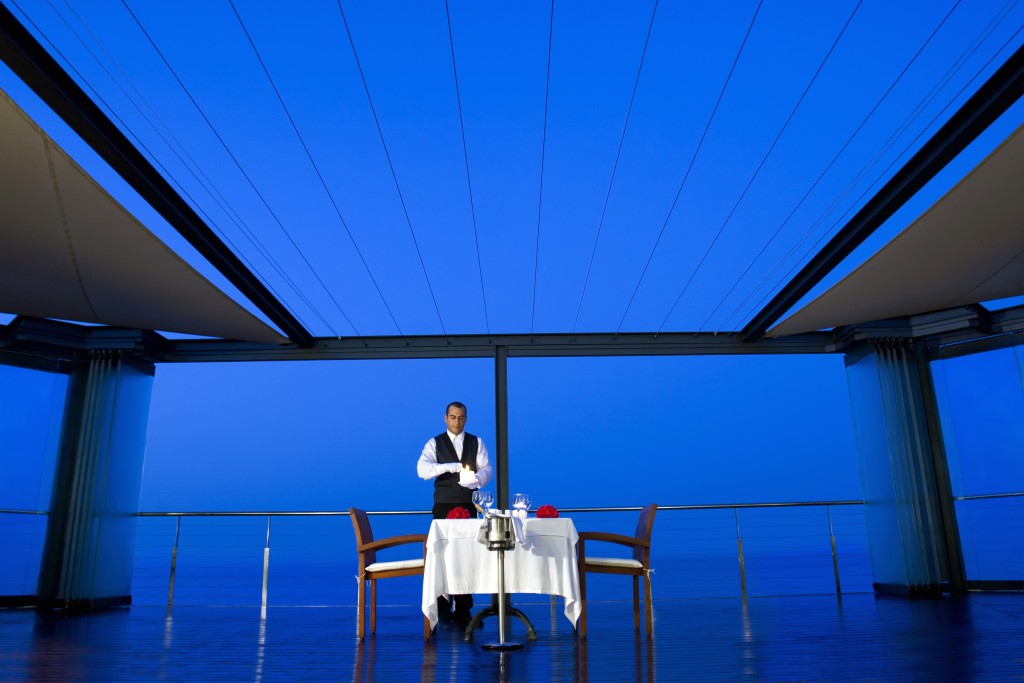 Image of a waiter working on a dinning table arrangement for a private party dinner.